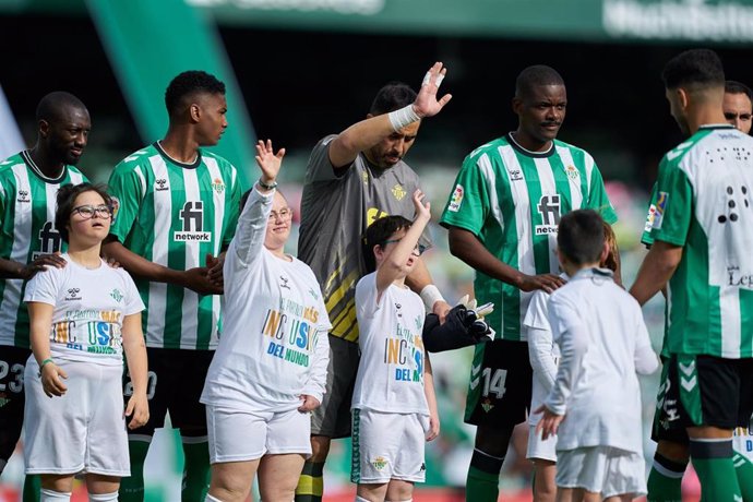 Archivo - Jugadores del Real Betis saltan al césped con menores con discapacidad antes de un partido de fútbol.