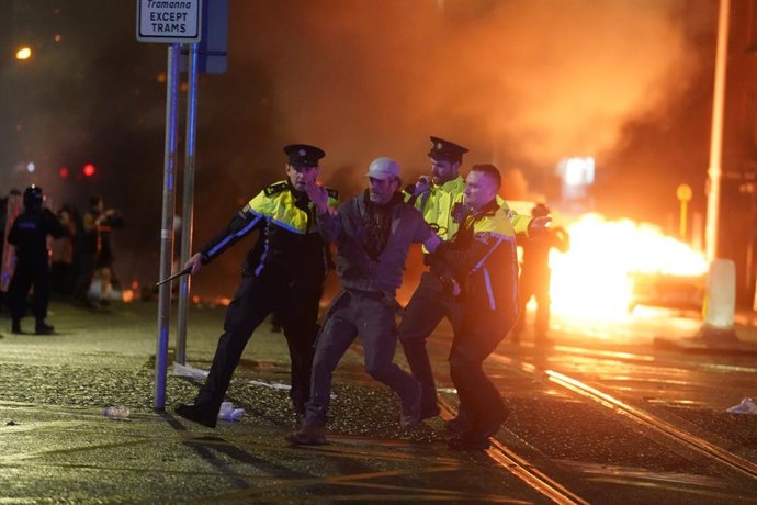 23 November 2023, Ireland, Dublin: Irish Garda riot police arrest a protester in Dublin city centre during protests following the stabbings earlier. Five people, including three children, were taken to hospital following a suspected stabbing outside a D