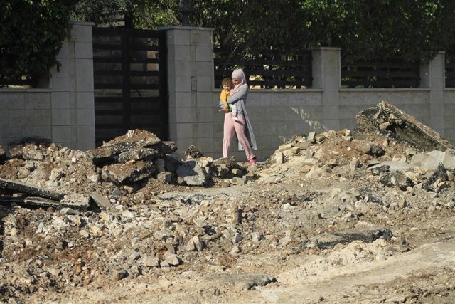 Una mujer camina junto a su bebé entre los escombros dejados por un ataque israelí sobre Yenín, en Cisjordania.