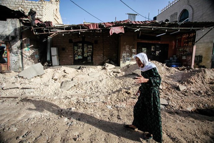 November 26, 2023, Jenin, Palestine: A woman walks past damaged buildings following an overnight Israeli incursion in the occupied West Bank city of Jenin. Five people were killed by Israeli army fire in Jenin, the Palestinian health ministry said, duri