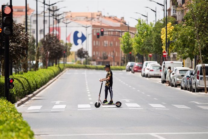 Archivo - Un joven cruza con un patinete eléctrico bajo el sol en la Calle Hellín, a 11 de julio de 2023, en Albacete