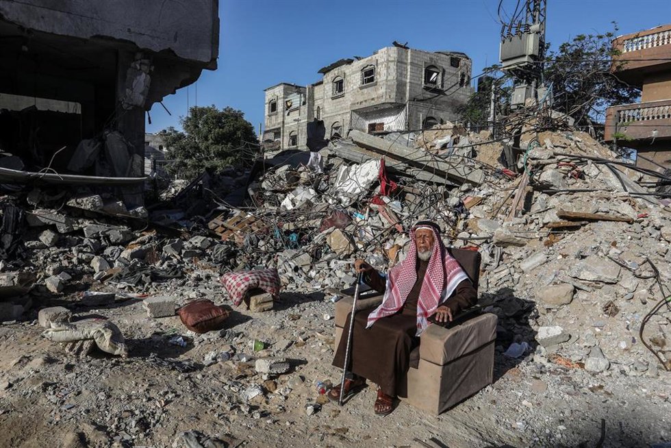 Un hombre palestino sentado sobre los escombros de una vivienda en Gaza.