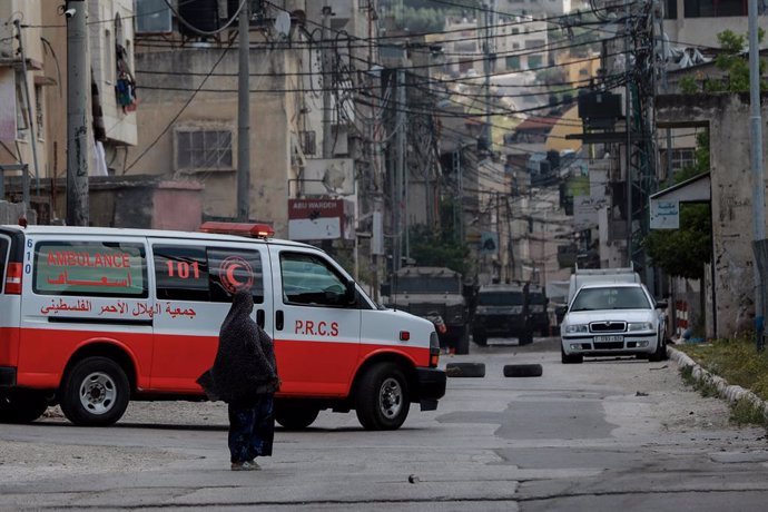 Archivo - 13 May 2023, Palestinian Territories, Nablus: A woman stands next to a vehicle of the Palestine Red Crescent Society during clashes between Palestinians and Israeli forces at the entrance to Balata refugee camp, east of Nablus, in the West Ban