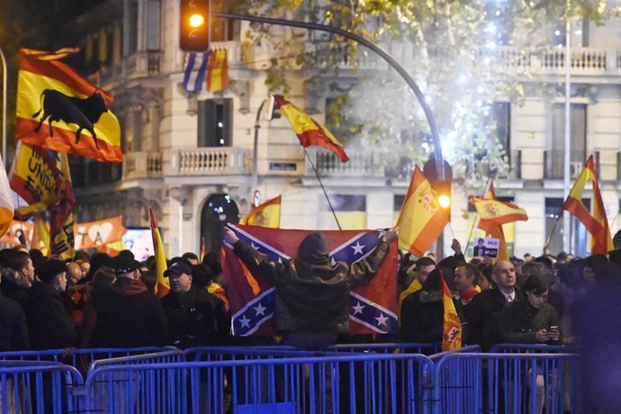Varias personas portan banderas españolas y una bandera confederada, durante la protesta convocada en la calle Ferraz 