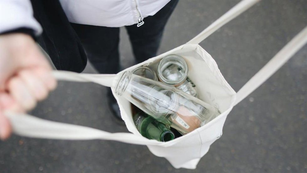 Una persona muestra envases de vidrio para su reciclaje.