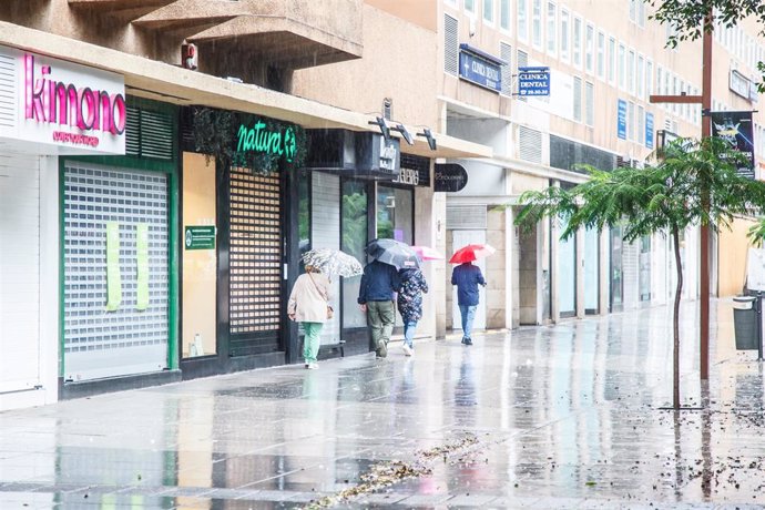 Archivo - Varias personas se cubren de la lluvia con un paraguas mientras caminan por una vía, a 25 de septiembre de 2022, en Las Palmas de Gran Canaria, Canarias (España). 