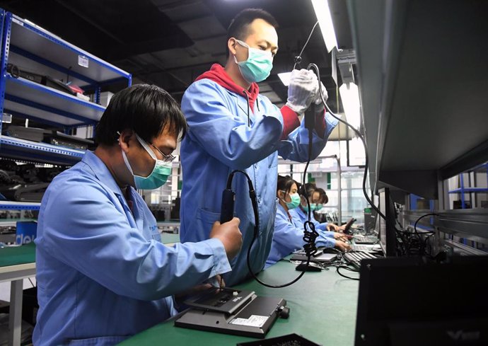 Archivo - Un grupo de trabajadores durante su turno en una fábrica de Pekín que se encarga de reparaciones electrónicas.