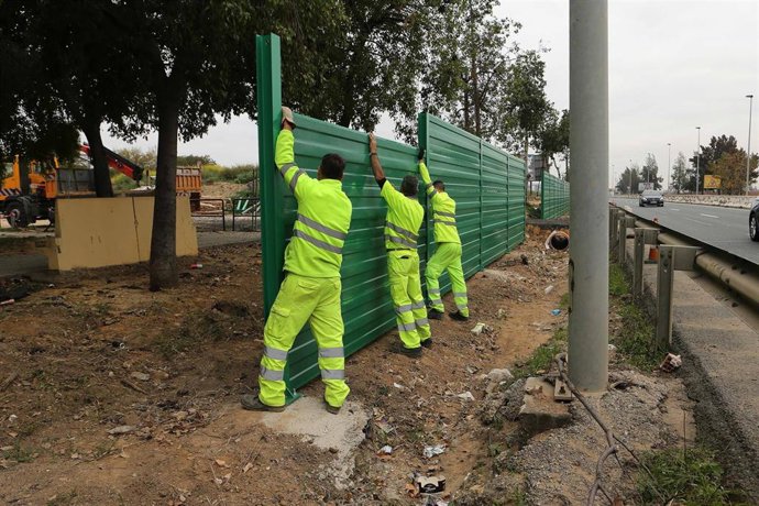 Operarios colocan pantallas contra el ruido en la carretera A-8028 a la altura del barrio sevillano de Palmete.