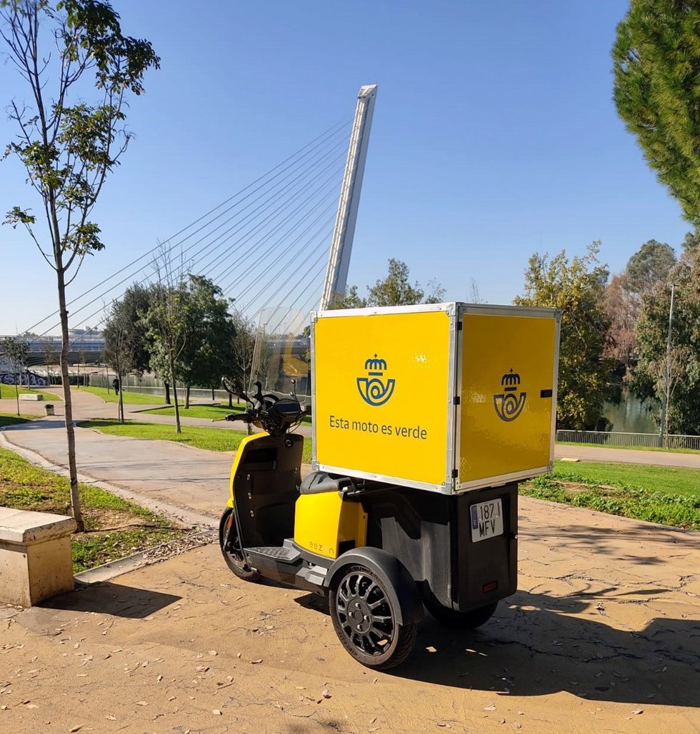 Triciclos eléctrico de Correos, con el puente del Alamillo al fondo, para mejorar el reparto de última milla.