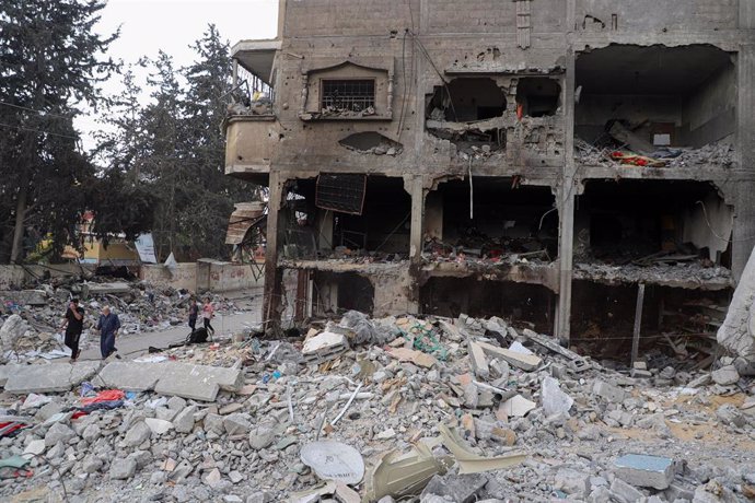 GAZA, Nov. 13, 2023  -- People walk past the rubble of buildings destroyed in Israeli airstrikes in the southern Gaza Strip city of Khan Younis on Nov. 12, 2023. 