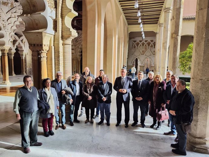 El consejero de Medio Ambiente y Turismo, Manuel Blasco,  con los alcaldes de los 13 municipios aragoneses que ostentan el sello de 'Los pueblos más Bonitos de España', en el Patio de los Naranjos