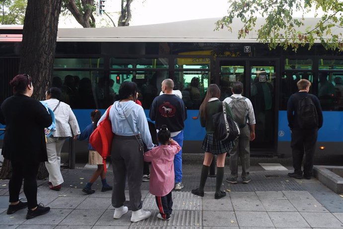 Archivo - Varias personas delante de un bus