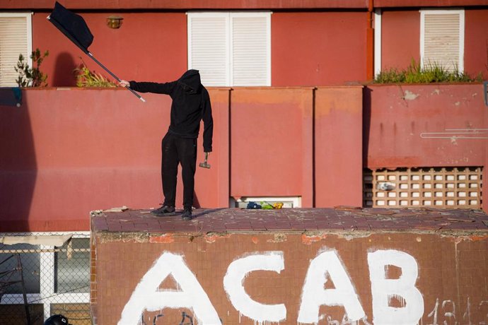 Un okupa con una bandera en los edificios de la Runa y el Kubo, en la plaza Bonanova, a 30 de noviembre de 2023, en Barcelona.
