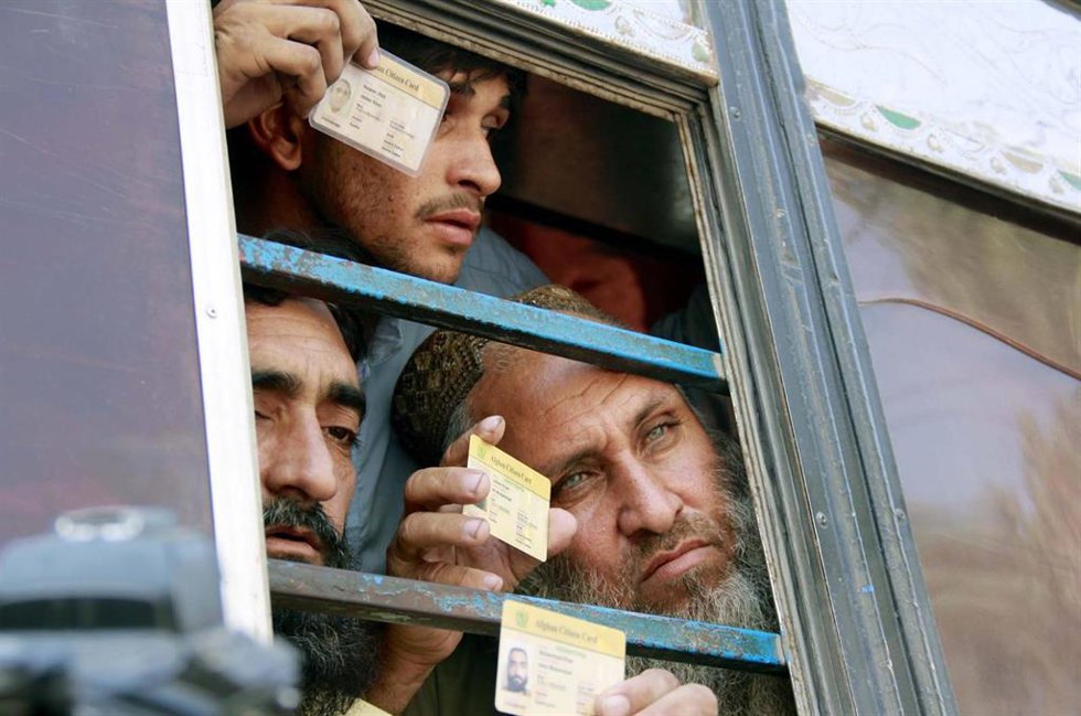 Ciudadanos afganos sostienen sus credenciales después de haber sido detenidos por la Policía paquistanía para su deportación,