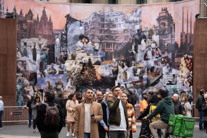 Unos visitantes se hacen fotografías delante del belén de la plaza Sant Jaume de Barcelona.