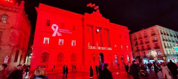 La fachada del Ayuntamiento de Barcelona iluminada de rojo por el Día Mundial de la Sida.