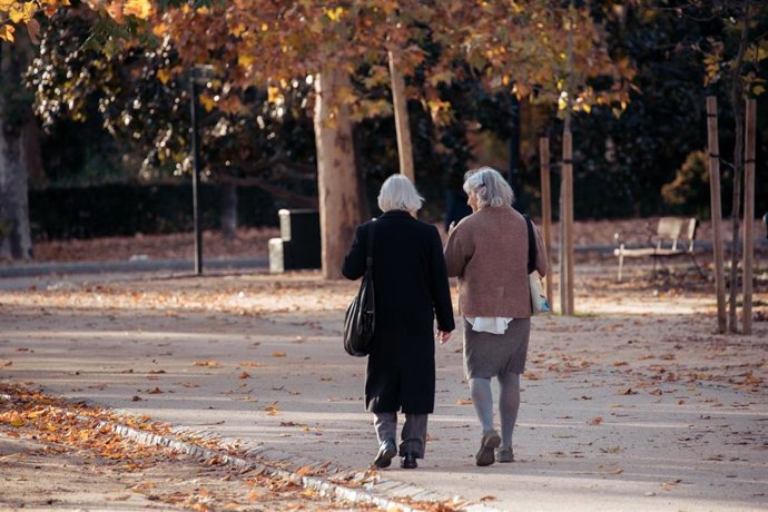 Dos mujeres mayores caminando por un parque.