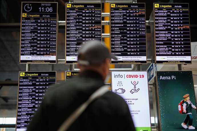 Archivo - Un hombre con mascarilla observa los paneles informativos de las salidas de los vuelos en el aeropuerto Adolfo Suárez Madrid-Barajas.