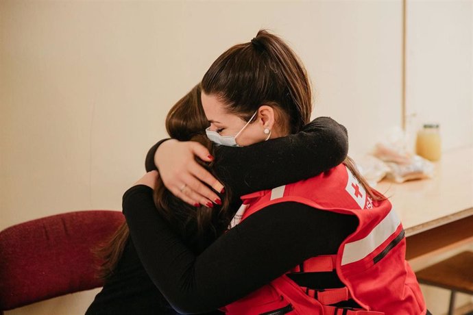 Archivo - Una voluntaria de Cruz Roja abraza a una mujer atendida por la ONG.