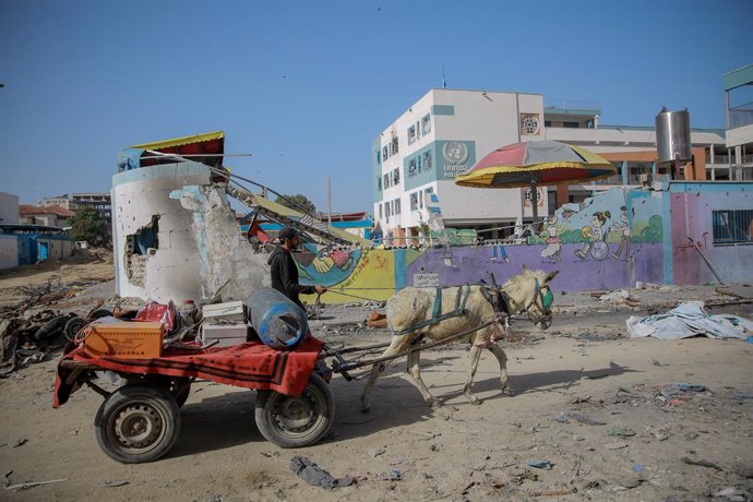26 November 2023, Palestinian Territories, Gaza City: APalestinian man rides a cart by a partially-destroyed UNRWAschool in Gaza City, on the third day of the truce between Israel and Hamas. Photo: Omar Ishaq/dpa
