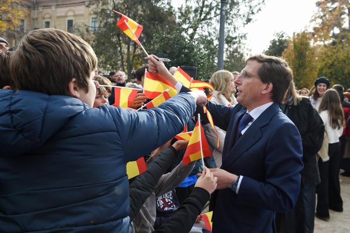 El alcalde de Madrid, José Luis Martínez-Almeida firma banderas de España a algunos niños en el Acto Institucional del Ayuntamiento con motivo del Día de la Constitución, en los jardines de la Transición Española