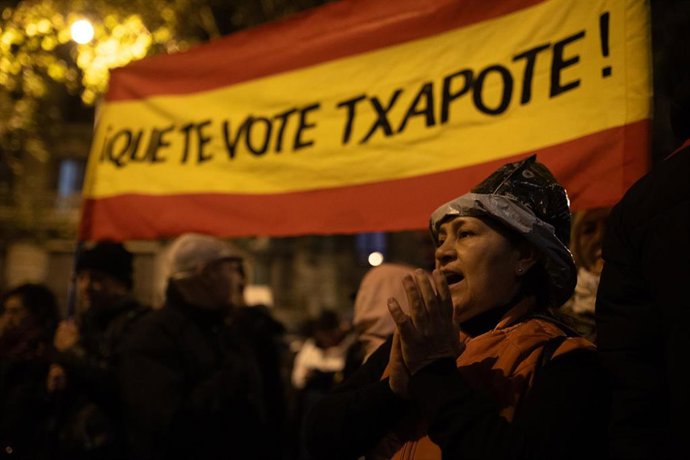 Una manifestante con la bandera de España y el texto "Que te vote Txapote", durante una protesta en la calle Ferraz