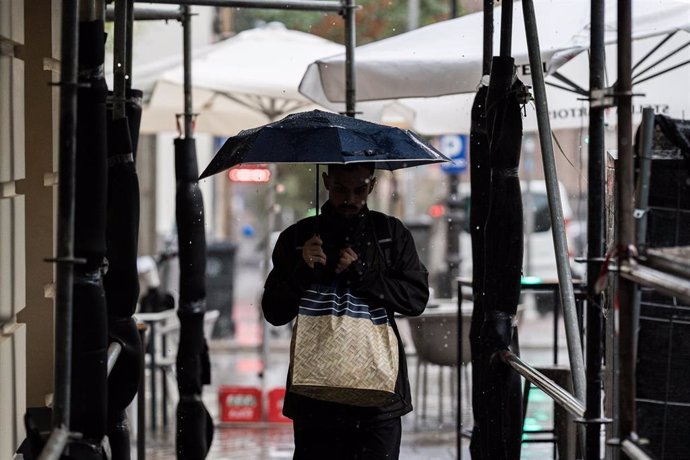 Archivo - Varias personas se resguardan de la lluvia con paraguas, a 3 de septiembre de 2023, en Madrid (España).   