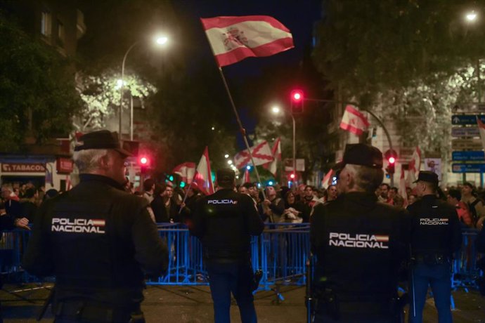 Decenas de manifestantes con banderas y carteles tras las vallas de seguridad y frente a varios agentes de policía, durante una manifestación contra la amnistía frente a la sede del PSOE en Ferraz, a 18 de noviembre de 2023, en Madrid (España). 