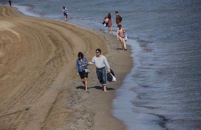 Archivo - Varias personas pasean por la orilla de la playa de La Malvarrosa