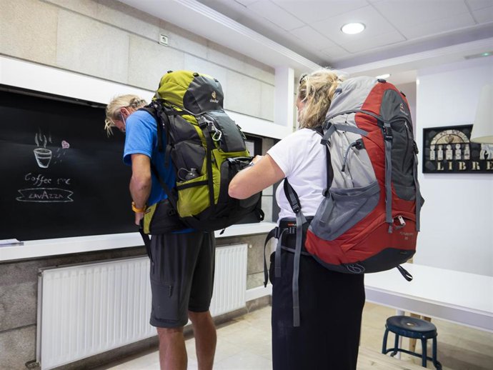 Archivo - Una peregrina busca su documentación en una mochila para acceder a un albergue, en Santiago de Compostela, a 9 de octubre de 2021, en Santiago de Compostela, A Coruña, Galicia (España). Galicia amplía desde este sábado el aforo en interiores, 