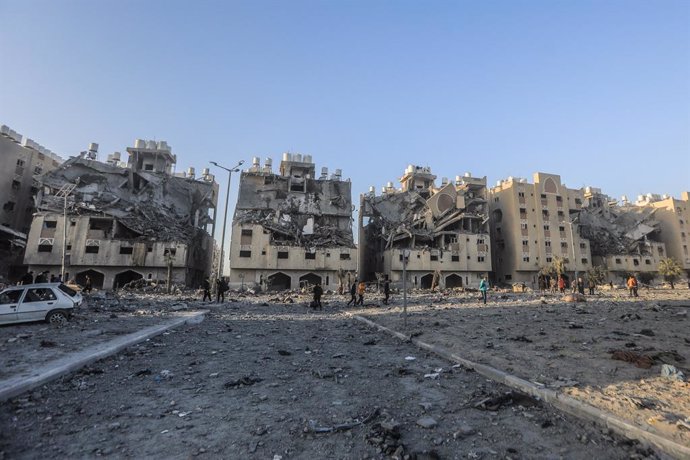 02 December 2023, Palestinian Territories, Khan Yunis: Residents of the Qatari-funded Hamad Town residential complex in Khan Yunis in the southern Gaza Strip carry some of their belongings as they flee their homes after an Israeli raid completely destro