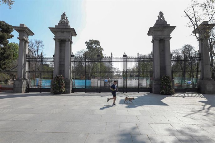 Archivo - Un corredor con su perro pasan frene a una de las entradas de El Retiro 