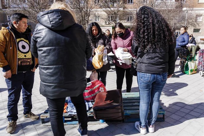 Archivo - Dos mujeres sujetan prendas de vestir durante la entrega de ropa de abrigo y zapatos nuevos a niños vulnerables, a 24 de febrero de 2023, en Madrid (España). 