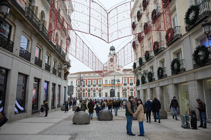Archivo - Varias personas en una calle comercial frente a la remodelada y peatonalizada Puerta del Sol, a 4 de diciembre de 2022, en Madrid (España). Con motivo del puente de la Constitución la Puerta del Sol ha quedado despejada y accesible para facili