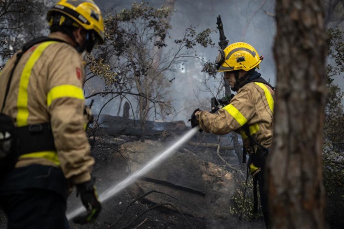 Archivo - Dos bomberos con una manguera para apagar el fuego del incendio en Argentona, a 24 de junio de 2021, Barcelona, Catalunya (España).
