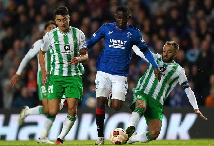Archivo - Dos jugadores del Betis tratan de arrebatar el balón a un jugador del Rangers, en el primer partido de Europa League disputado en Glasgow.