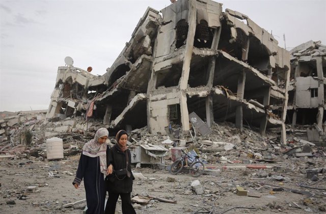 November 25, 2023, Gaza City, Gaza Strip, Palestinian Territory: Displaced Palestinians, taking shelter in hospitals and schools until the start of the 4-day humanitarian pause, walk as they carry items remain intact amid the destruction caused by Israeli