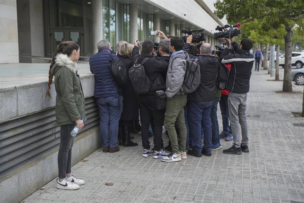 La joven que fue víctima de abusos del exmarido de Oltra mira a su abogado mientras atiende a los medios a las puertas de la Ciudad de la Justicia, donde ella declara como testigo en la causa en la que se investiga un presunto encubrimiento de los abusos