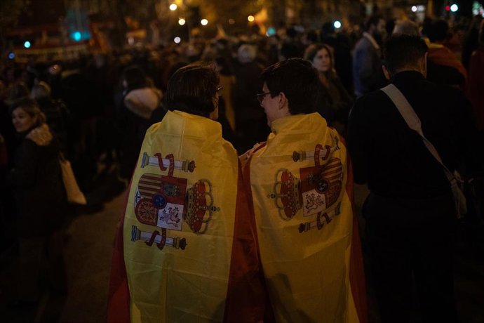Dos mujeres con la bandera de España durante una manifestación contra la amnistía frente a la sede del PSOE en Ferraz