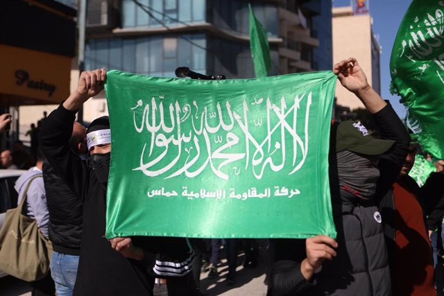Palestinos muestran una bandera de Hamás durante una manifestación en la ciudad cisjordana de Hebrón en apoyo a la Franja de Gaza ante la ofensiva militar de Israel