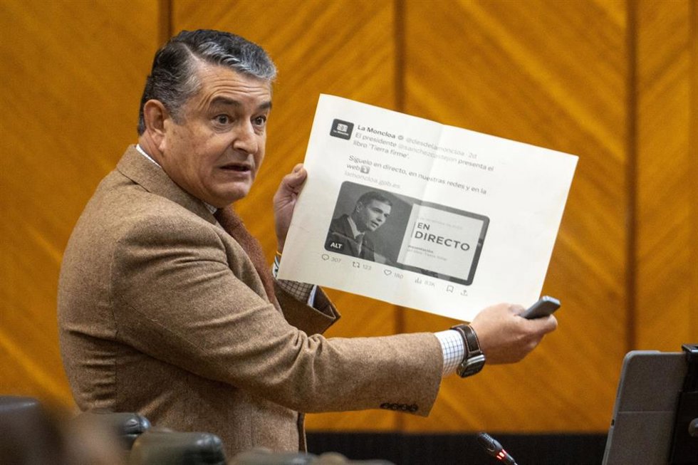 El consejero de la Presidencia, Antonio Sanz, este jueves en el Pleno del Parlamento mostrando la imagen de la web de La Moncloa sobre la retransmisión de la presentación del libro del presidente del Gobierno, Pedro Sánchez.