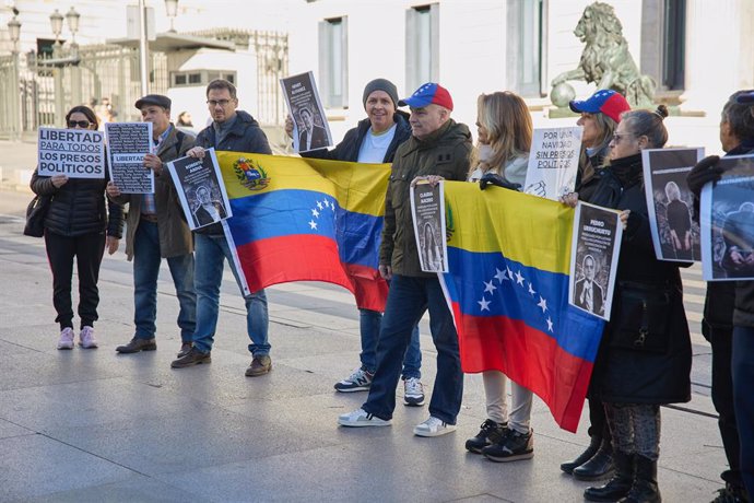 Venezolanos sujetan pancartas y la bandera de Venezuela durante una concentración con motivo del éxito de la Primaria y del fracaso del referéndum sobre el Esequibo, en la Plaza de Las Cortes, a 14 de diciembre de 2023, en Madrid (España). La disputa entr
