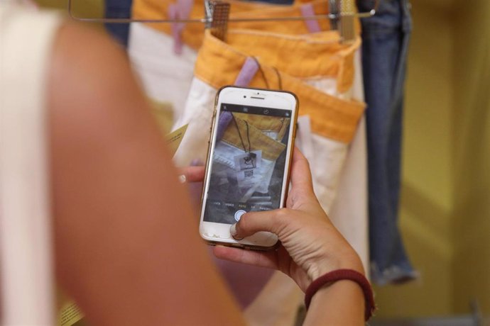 Archivo - Una mujer toma una foto de la etiqueta de una prenda de ropa 