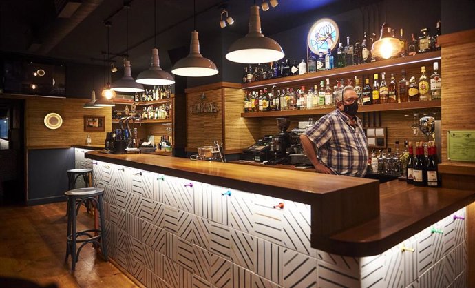 Archivo - Un trabajador en la barra de un bar vacía