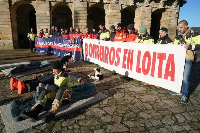 Bomberos sujetan una pancarta durante una concentración en forma de protesta pacífica, en la Praza do Obradoiro, a 15 de diciembre de 2023, en Santiago de Compostela, A Coruña, Galicia (España). Los bomberos comarcales inician una concentración indefini