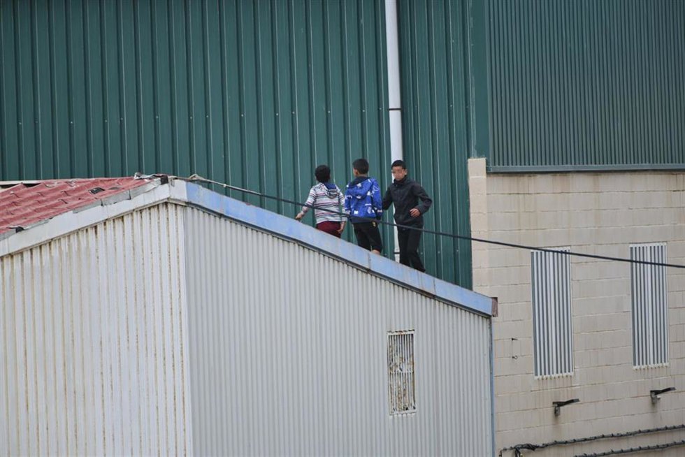 Archivo - Varios niños caminan por un tejado al tratar de escapar de la nave de primera acogida del polígono del Tarajal en Ceuta. 