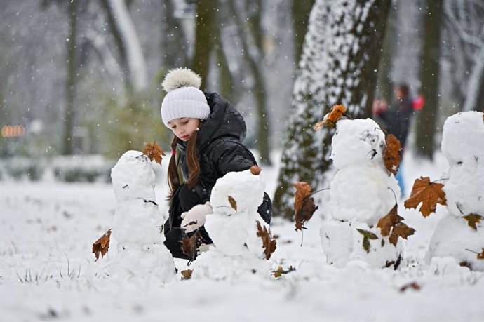 November 28, 2023, Lviv, Ukraine: LVIV, UKRAINE - NOVEMBER 28, 2023 - A girl makes a snowman in a snow-drifted park, Lviv, western Ukraine.