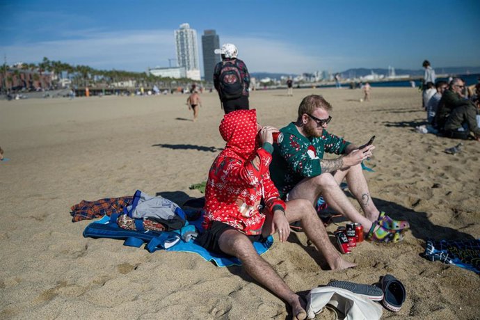 Archivo - Unos turistas con jerséis de Navidad toman unas latas de cerveza en la playa de la Barceloneta, a 25 de diciembre de 2022, en Barcelona, Cataluña (España).