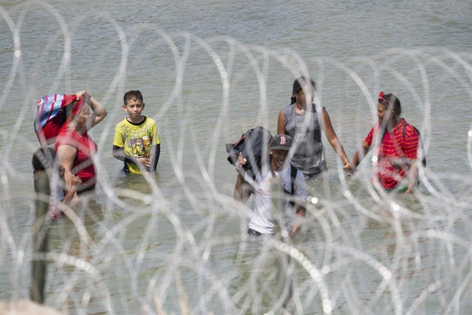 Archivo - August 21, 2023, Eagle Pass, TX, United States: Miigrants from Central America  look for an opening in the concertina wire barrier south of Eagle Pass where a 1000-foot string of buoys has been placed in the river to deter crossing the Rio Gra