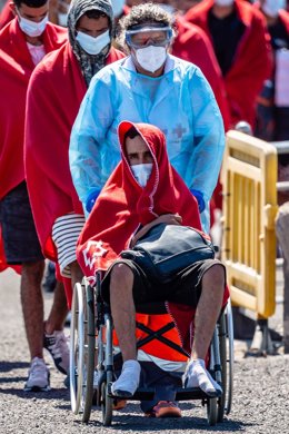 Archivo - Una trabajadora de la Cruz Roja con uno de los 34 migrantes rescatados por Salvamento Marítimo, en el Muelle de La Cebolla a 1 de septiembre de 2021, en Lanzarote, Islas Canarias (España). La patera con los migrantes fue avistada al norte de Arr